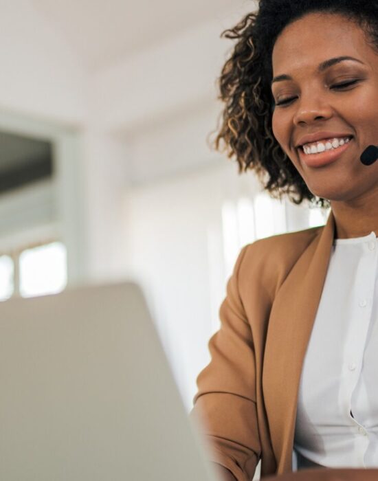 Low angle portrait of a happy woman wearing headset using laptop. Low angle portrait of a happy woman wearing headset using laptop.